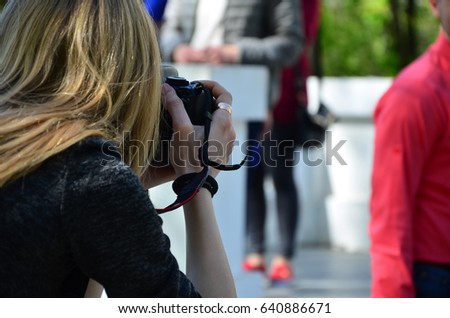 Wedding photographer in the process of his work. Professional photographer shoots a wedding ceremony. A young girl looks into the camera's viewfinder