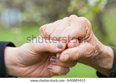 Close up picture of a young woman's hands holding an elderly female's hands
