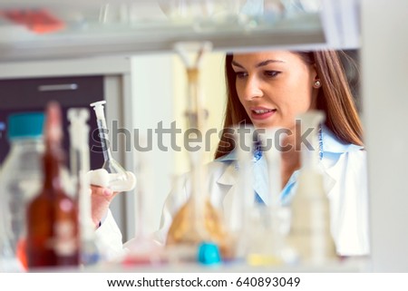 Woman scientist behind lab glassware. Scientist carrying out experiment in research laboratory