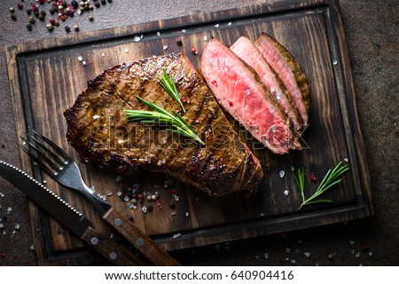 Fresh grilled meat. Grilled beef steak medium rare on wooden cutting board. Top view. Royalty-Free Stock Photo #640904416
