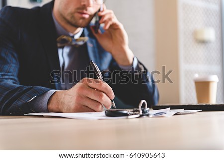 male writing at table while talking on phone Royalty-Free Stock Photo #640905643