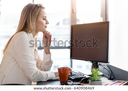 Successful young lady looking at pc screen