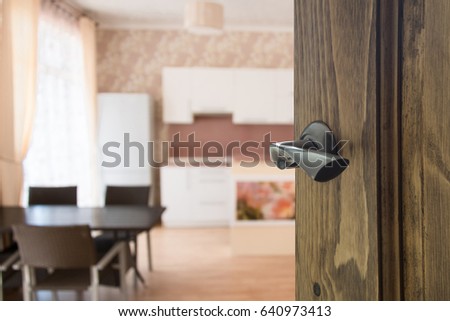 Opened wooden door to modern dining room.