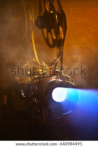 Old movie projector with the film on the brick wall background