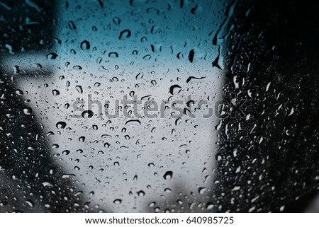 abstract image of rain drops on car window focusing on the rain droplets on the traffic jam in the evening.