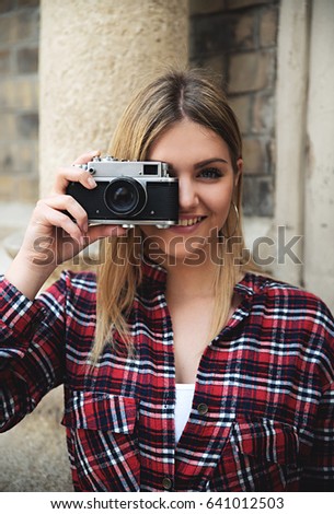 Girl taking photos with retro camera ans smiling