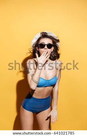 Picture of shocked young lady in swimwear isolated over yellow background. Looking at camera.