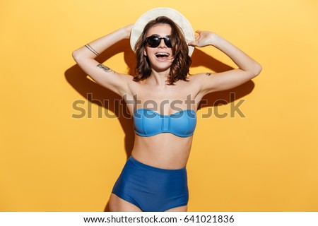 Picture of happy young woman in swimwear isolated over yellow background. Looking at camera.
