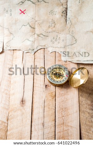 Compass on wood table with fake abstract Treasure map