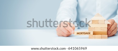 Mortgage concept. Financial agent complete wooden model of the house with last piece with text mortgage. Royalty-Free Stock Photo #641065969
