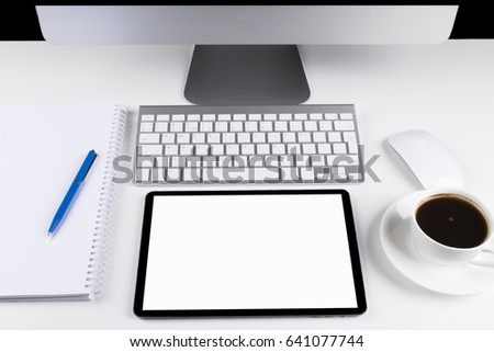 Office table with computer, wireless computer keyboard and mouse, cup of coffee, tablet computer.copy space notebook. empty screen
