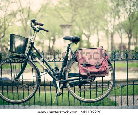 Vintage messenger bicycle in a fence in a park in Paris