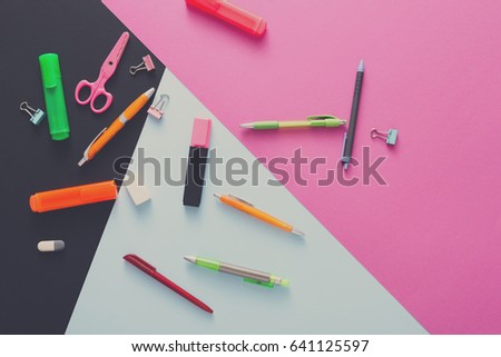 Stationery supplies and devices on pop art background. Top view flat lay mockup of creative work space at modern office with markers, rubbers, pens, scissors and binder clips