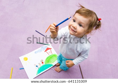 The small beautiful girl paints on a paper