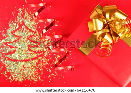 Big red gift with a golden ribbon and bow next sequins and packing tape