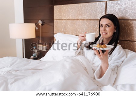 Happy attractive woman taking pleasure in her breakfast
