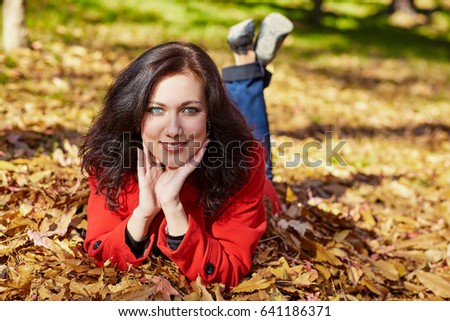 Beautiful woman lying on a yellow leaves in park