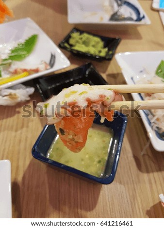 Raw Salmon fish and Octopus in chopsticks and spicy seafood green sauce