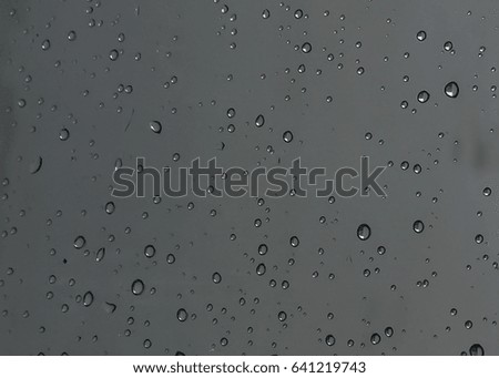 Rain drops, water drops of rain on a window glass with blurred dark background