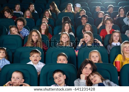 Low angle shot of little kids watching movie at the cinema looking amused and interested copyspace lens flare light childhood leisure activity people holidays carefree fascination concept.
