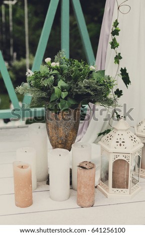 Wedding reception flower decorations, rustic style. Bridal bouquet and candles on wooden vintage background, outdoors, objects