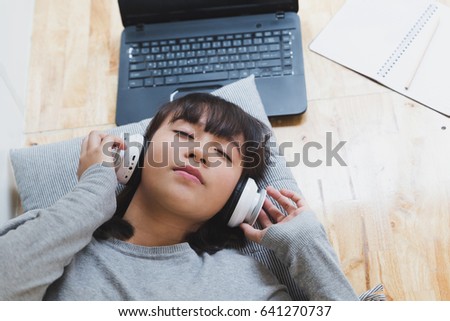 asian girl female teenager student lying and listening to music from headphone - lifestyle and education concept
