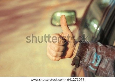 arm in the car with thumbs up. 