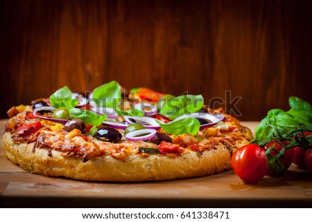 Traditional homemade pizza with tomatoes, olives and basil
