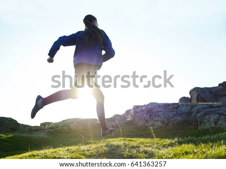 Young Woman Running on the Rocky Mountain Trail at Sunset. Active Lifestyle Concept