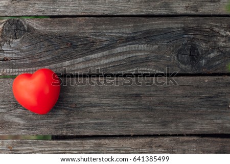 Red volumetric heart as a symbol of love rests on wooden grey background