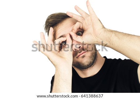 Handsome man looking through hands, making binoculars. Isolated on white.