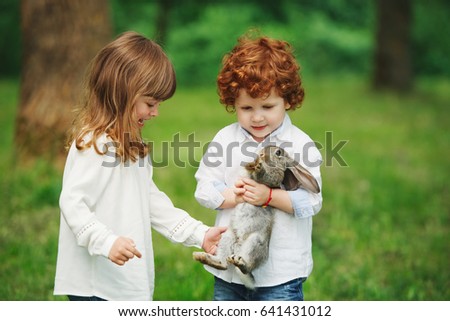 photo of little boy and girl playing with rabbit