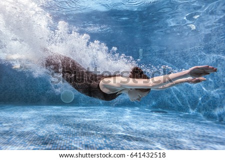 Woman goes in for sports in the pool, she dives underwater. Royalty-Free Stock Photo #641432518