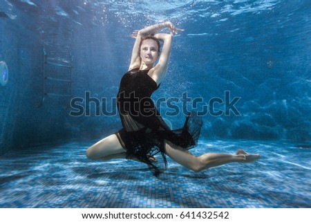 Woman in a dress is dancing under the water in the pool, she is engaged in sports underwater dances.