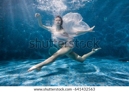 Woman dances underwater sports dance, her dress fluttering under the water. Royalty-Free Stock Photo #641432563