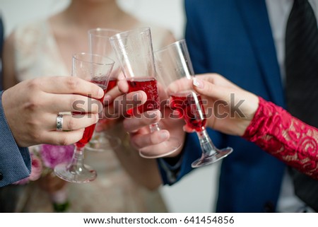 Close up of hands clinking with red champagne