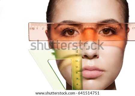 Close-up measure the girl's face and the shape of the eyes with rulers before the plastic surgery to change the proportions. Isolated on white background