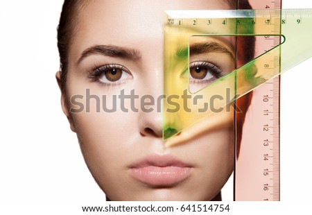 Measuring the proportions of a young woman's face with color rulers before a plastic surgery. Isolated on white background