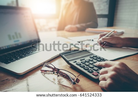 Close up Businessman and partner using calculator and laptop for calaulating finance, tax, accounting, statistics and analytic research concept Royalty-Free Stock Photo #641524333