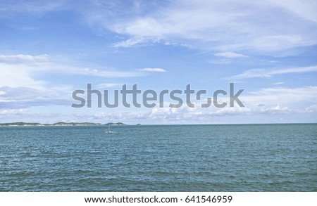 White clouds on blue sky over calm sea. 