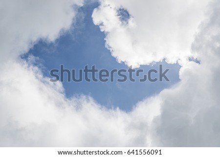 Sky with white and dark clouds background. The clouds make the picture like two people are kissing.