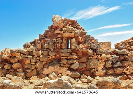 Part of a fortress wall of destroyed Venetian fort of Gramvousa of Crete on blue sky with clouds background