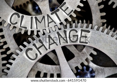 Macro photo of tooth wheel mechanism with CLIMATE CHANGE letters imprinted on metal surface