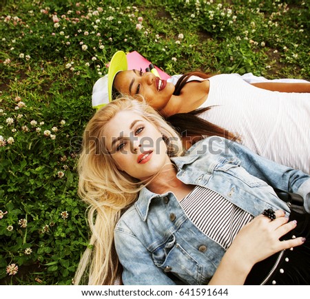 two young pretty teenager girls best friends laying on grass mak