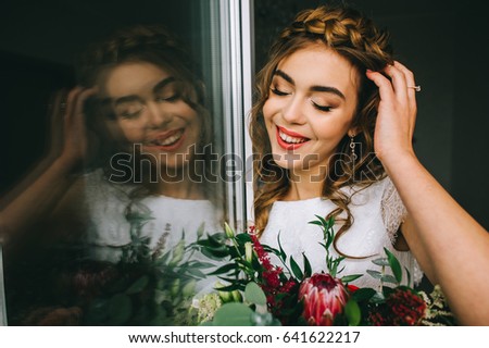beautiful bride with a bouquet of flowers by the window