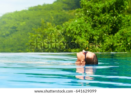 Attractive young woman relaxing in the swimming pool of a spa, on a summer day. Summer travel holiday concept, with happiness and emotions.