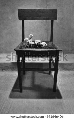Black and white photo of wooden chair with flowers on seat