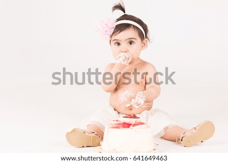 Child girl destroying her birthday cake while sitting on the floor