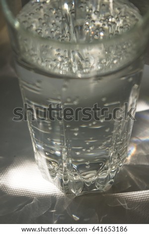 transparent faceted glass with bubbly water in the sun refracted light