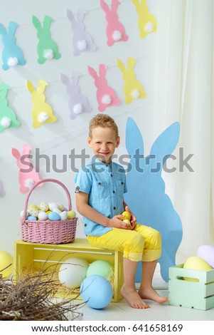smiling little boy in easter decorations.Kids celebrate Easter.  Home decoration, pastel bunny banner, colorful Easter eggs and flowers.